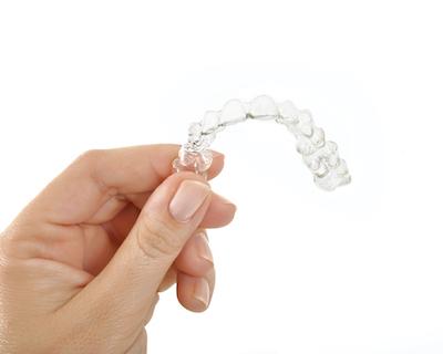 person holding Invisalign clear aligners