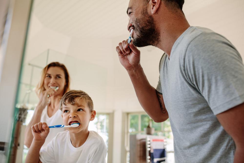 family of three brushing teeth