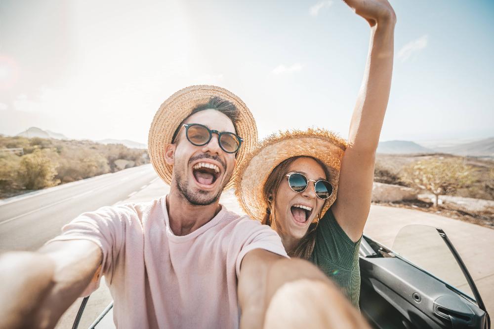 man and woman smiling while riding in a convertible