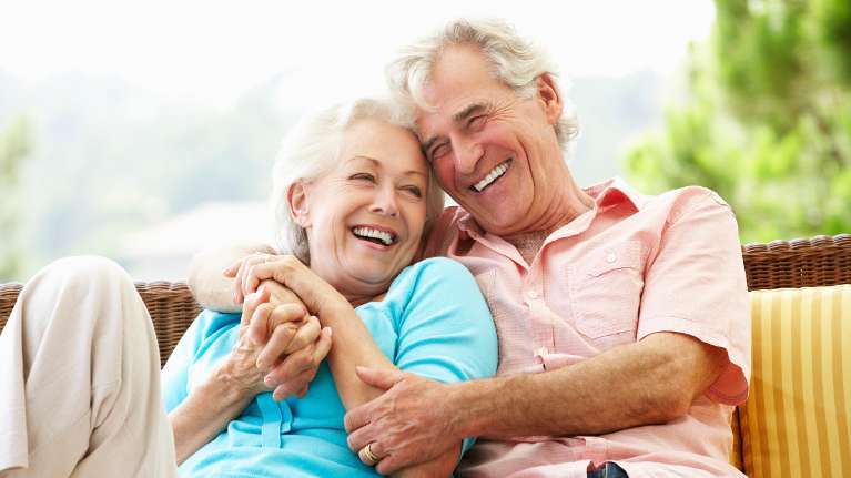 older man and woman snuggling on an outdoor couch